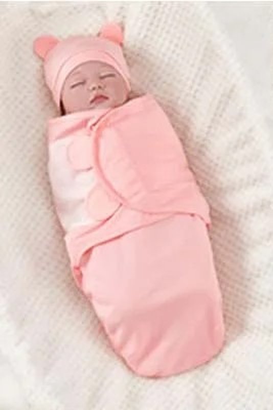 Sleeping baby in a pink Swaddle Buddy and bear-ear hat